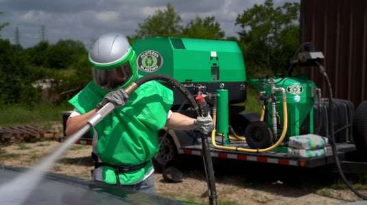 Man using Dustless Blasting's mobile sandblasting trailer