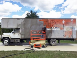 orange paint being removed from a large moving truck
