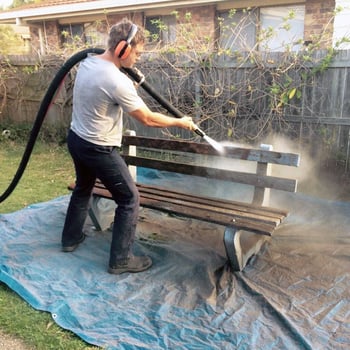 abrasive blasting the grime and paint off a wooden bench