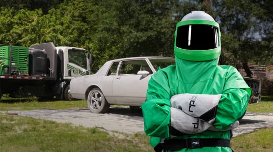Person in sandblasting protective equipment working on car restoration.