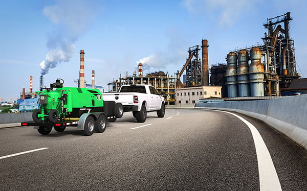 A Dodge Ram driving down the highway with a Dustless Blasting machine attached 