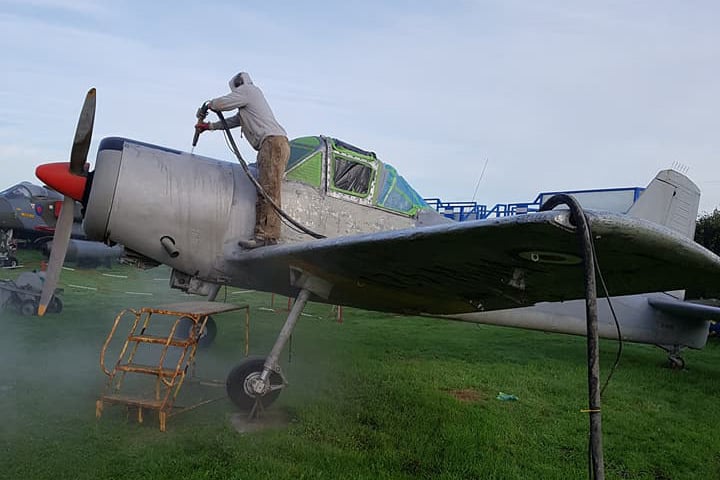 man standing on small plane and abrasive blasting