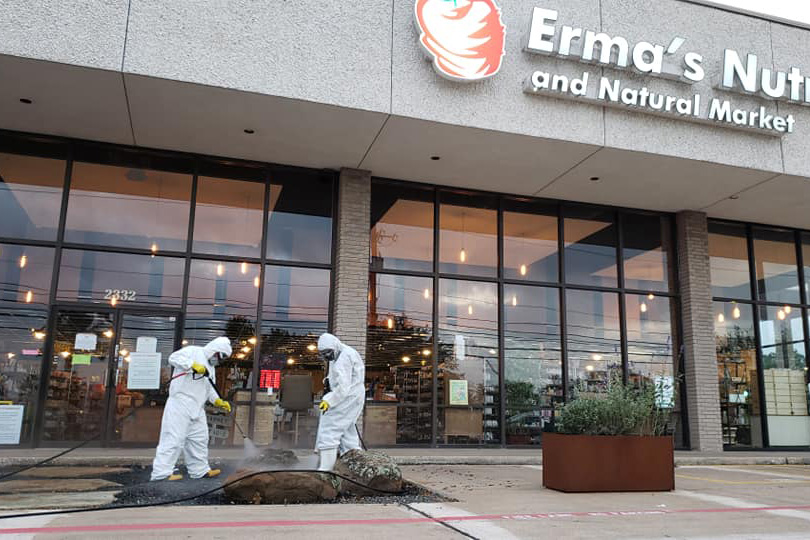 two men in hazmat suits applying vapor disinfectant at a store