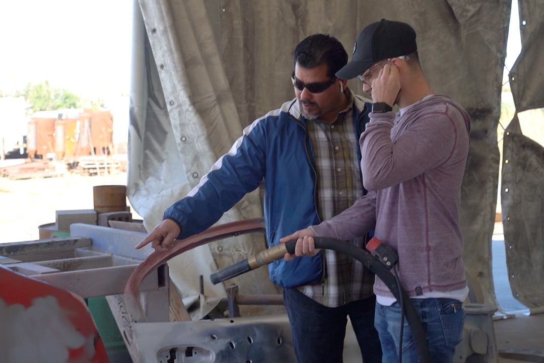 two men holding blast hose and pointing