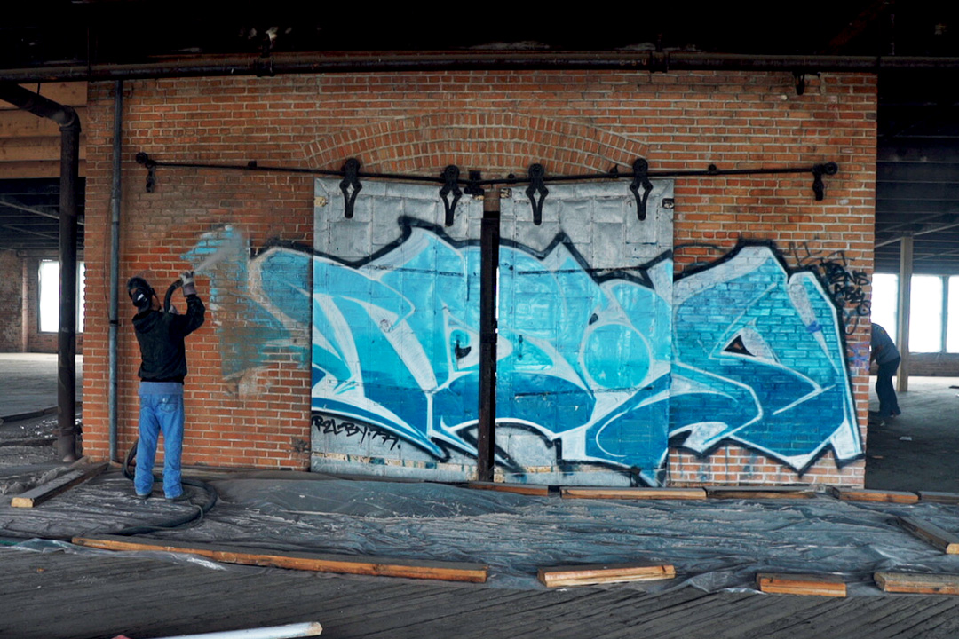 blue graffiti being stripped from brick wall